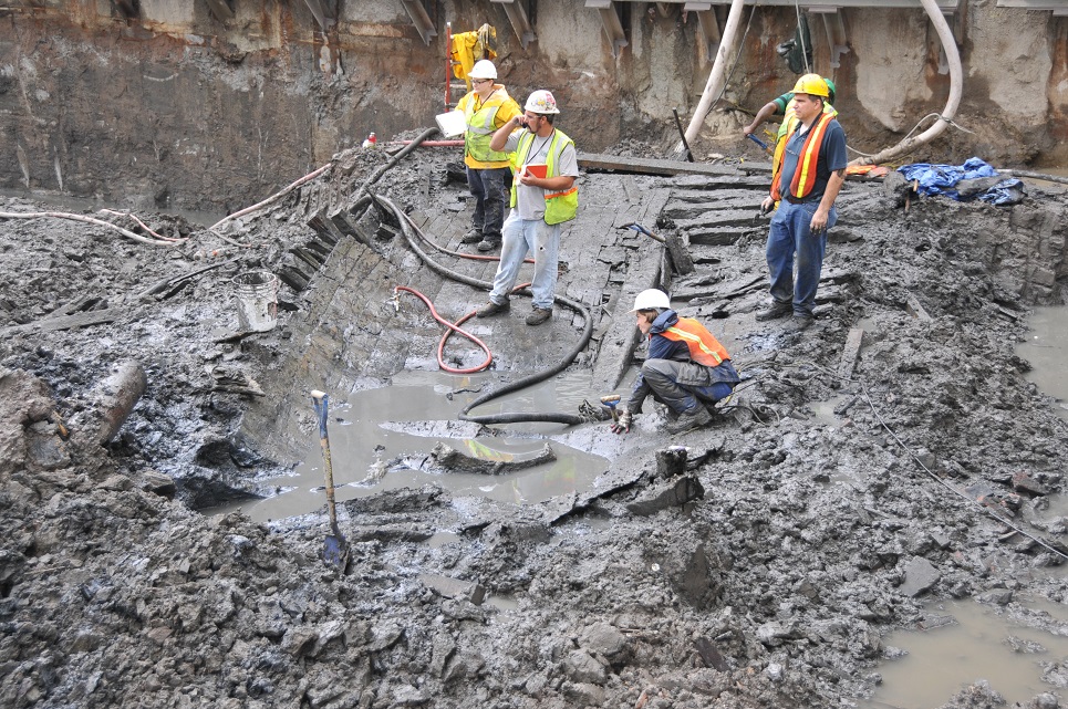 Construction workers stand atop the muddy remains of a ship discovered during the excavation of the World Trade Center site.