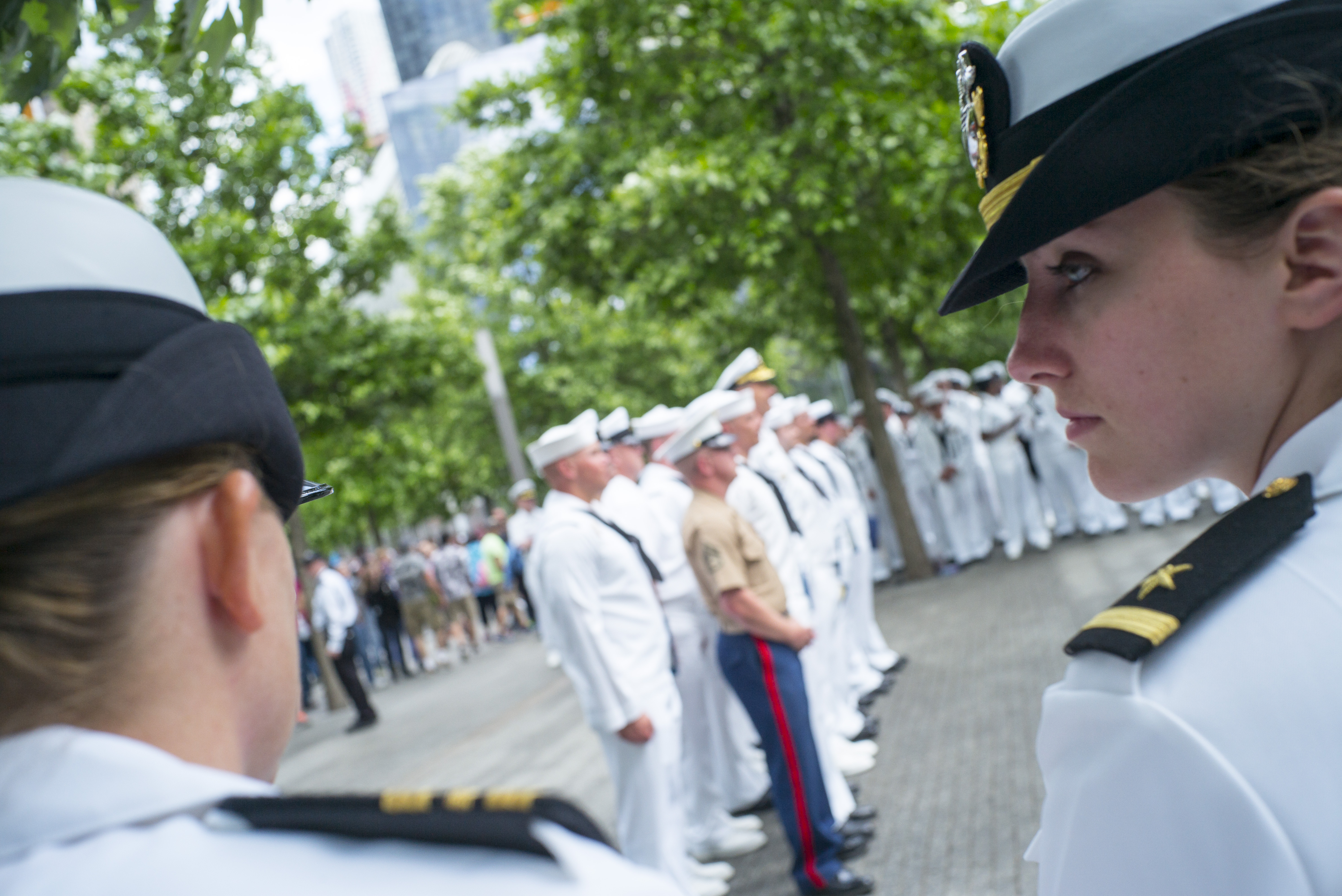 Members of the Navy gather on the Memorial plaza for a reenlistment ceremony. Dozens of them are dressed in their formal white uniforms.