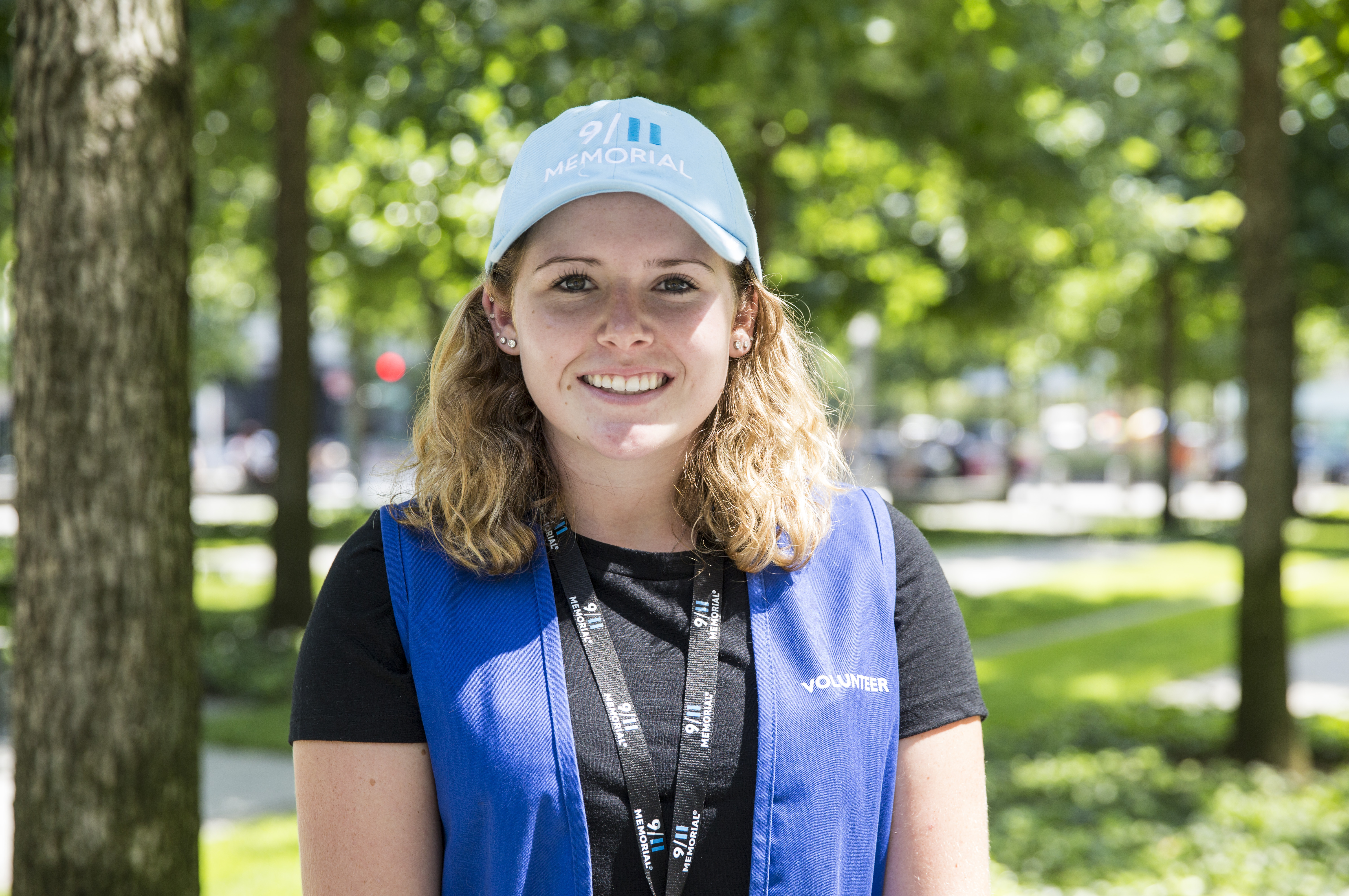 9/11 family member and volunteer Rose Fay smiles in her volunteer outfit during a sunny day on Memorial plaza.