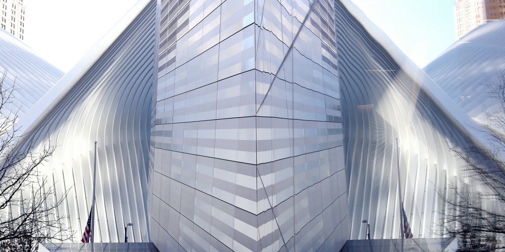 The bright white Oculus transportation hub reflects off a glass facade of the 9/11 Memorial Museum.