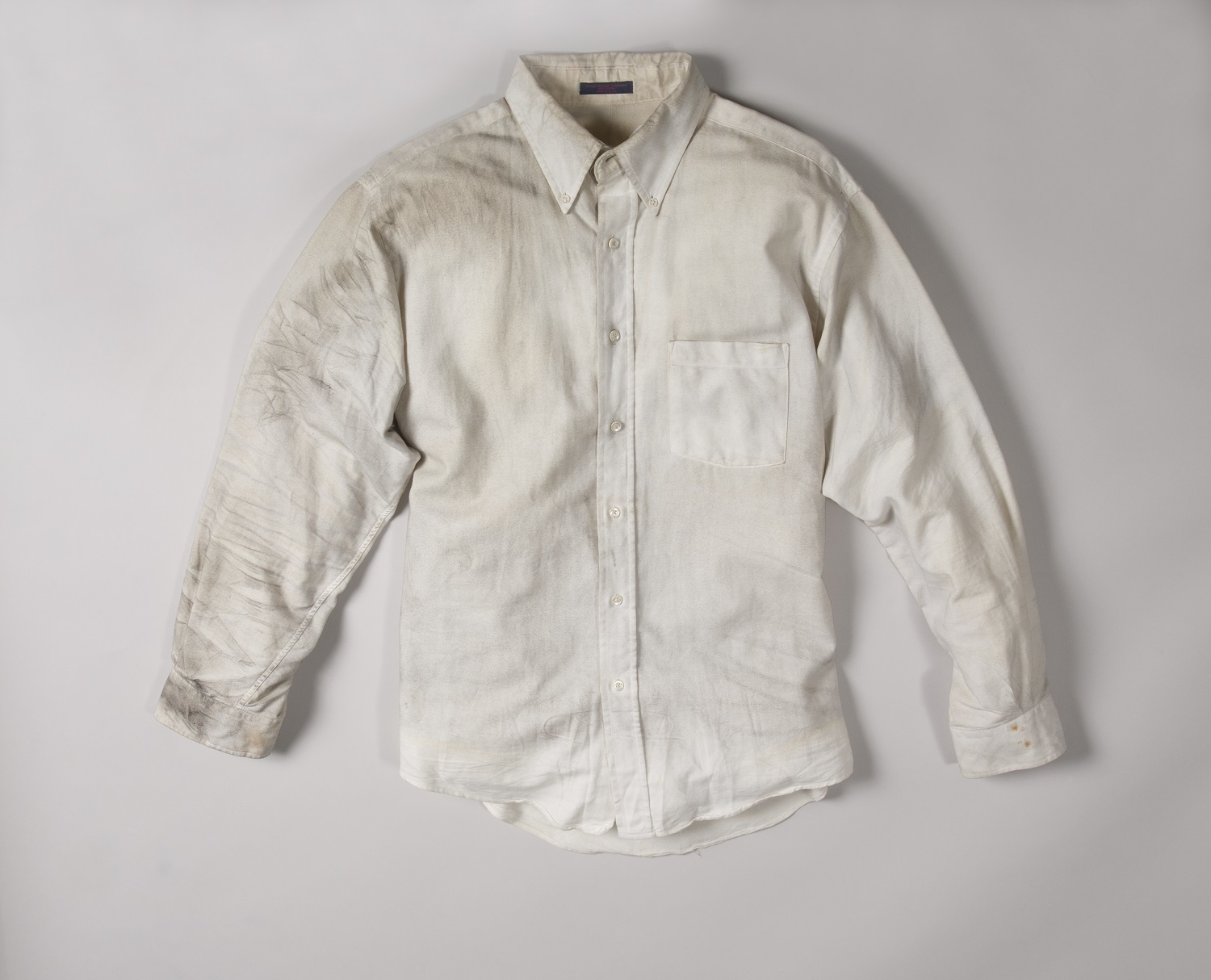 A smoke-stained white dress shirt worn by Walter Travers on February 26, 1993 is displayed on a white surface at the Museum.