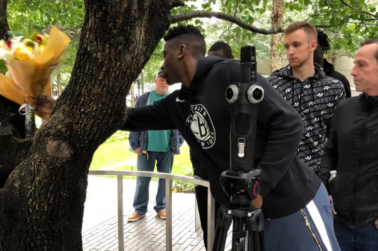 Players for the Brooklyn Nets visit the Survivor Tree on the Memorial. One of them places a bouquet of flowers on the tree.