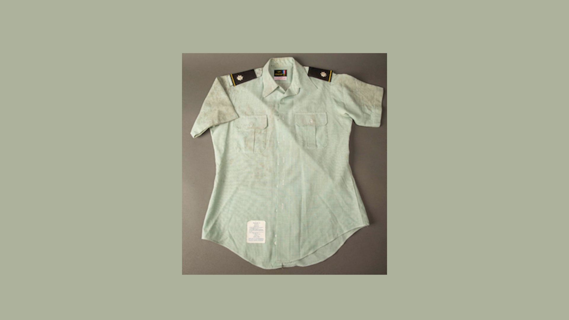 Light green short-sleeved military shirt laid out on gray background