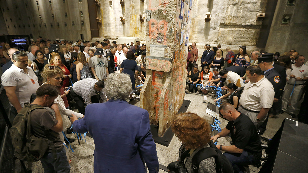 Dozens of people surround the Last Column in Foundation Hall as some of them place blue ribbons on the railing surrounding it to honor rescue and recovery workers.