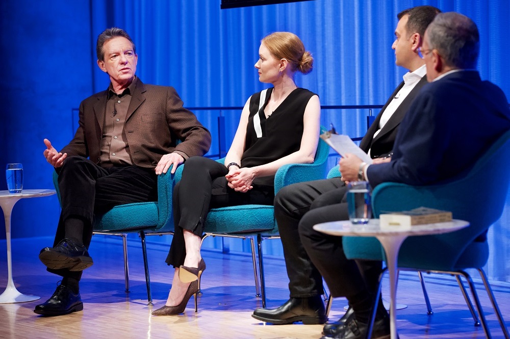 Three men and a woman take part in a moderated discussion on stage at the Museum.