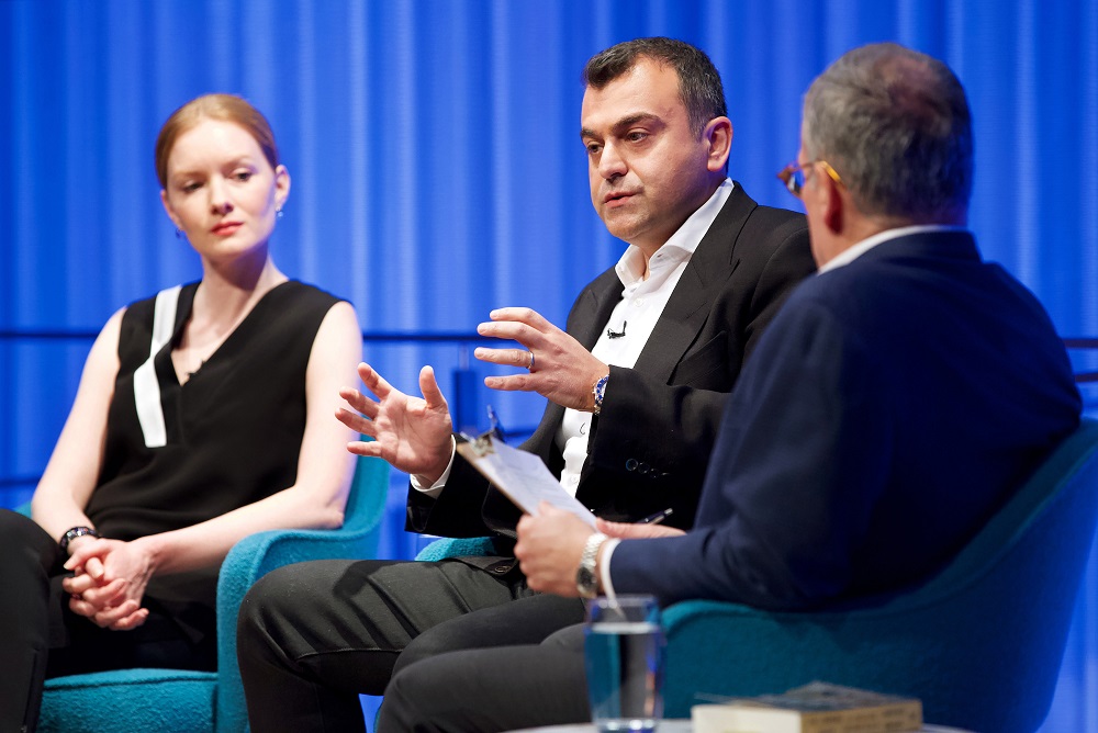 Three men and a woman take part in a moderated discussion on stage at the Museum.