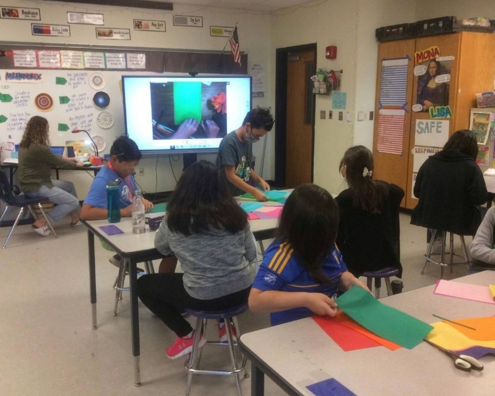 Students at work on a classroom project, making flowers out of tissue paper and pipe cleaner