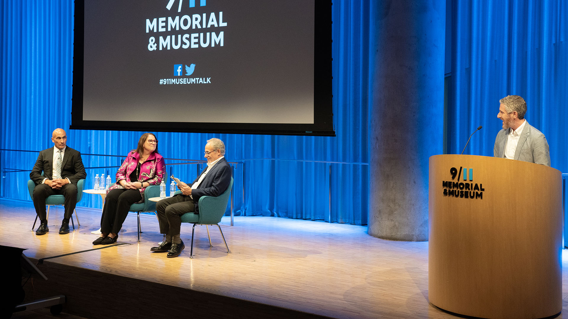 From left: John Liguori, Mary E. Galligan, and Clifford Chanin on stage with Noah Rauch at podium