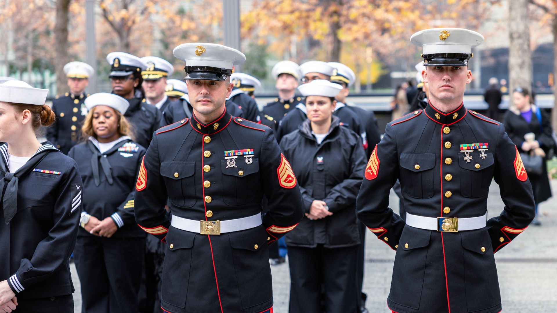 Group of uniformed military men and women stand at attention on the plaza