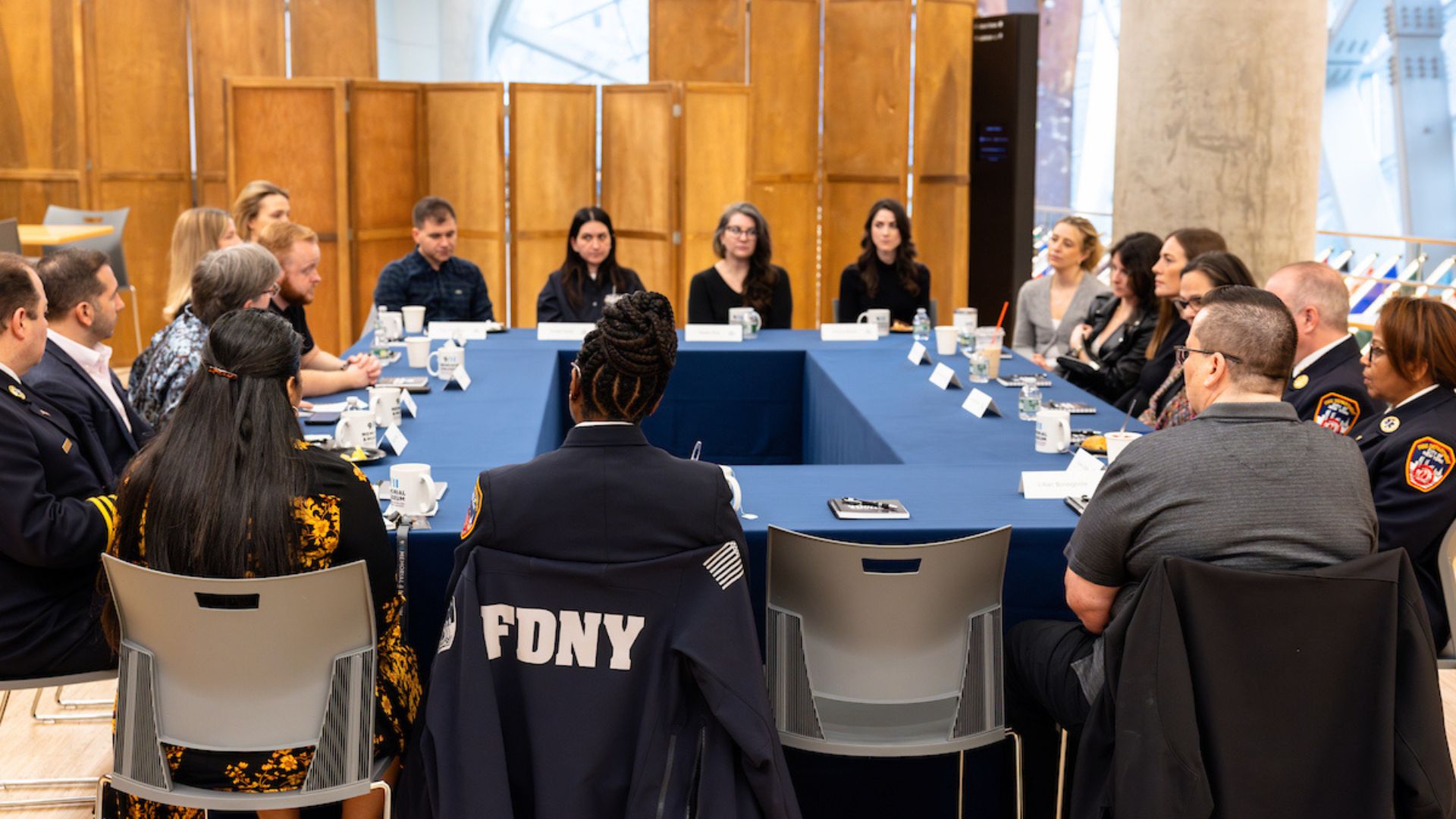 A large group of Visionaries and FDNY officers sit around a conference table