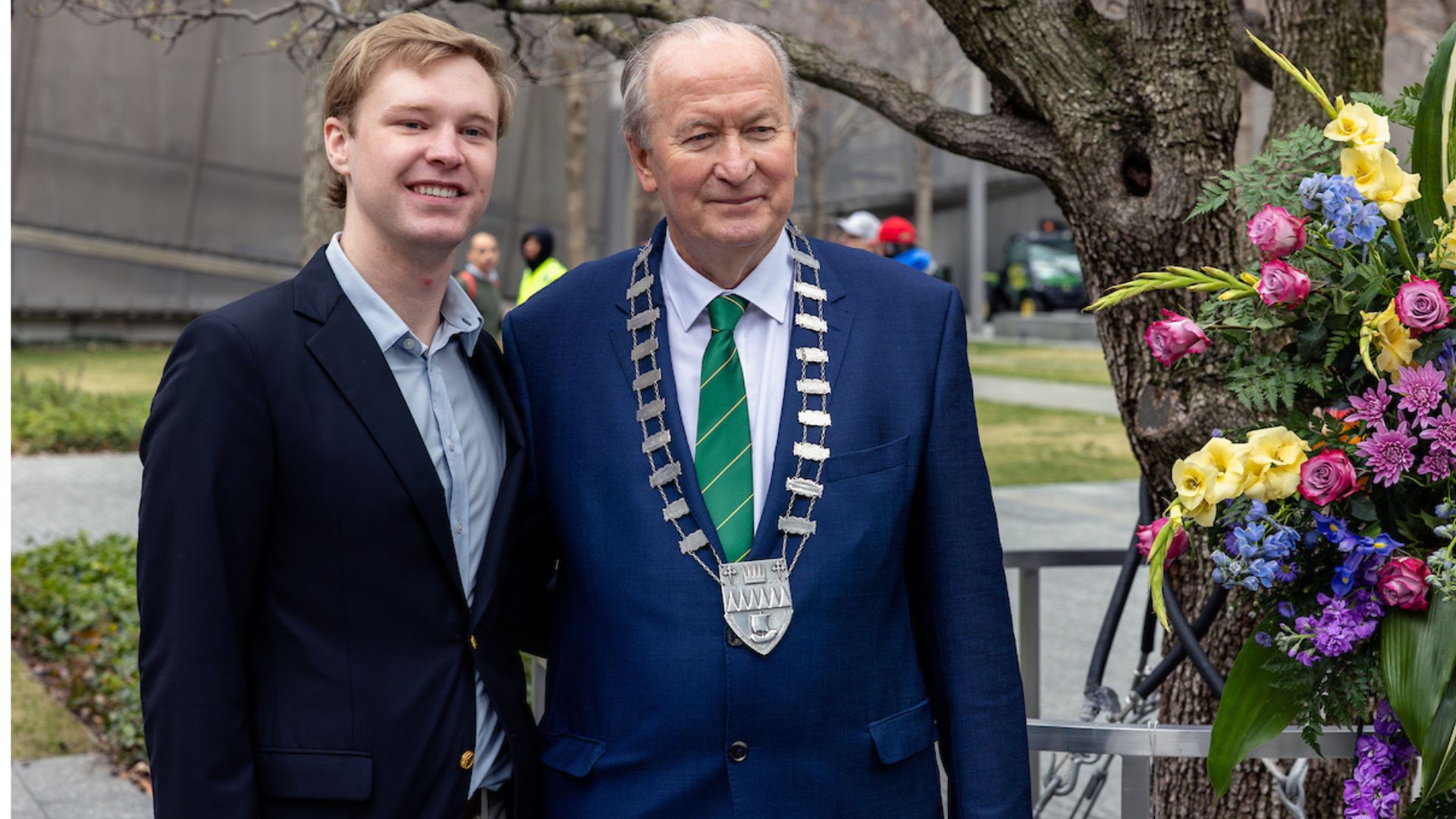 A Visionary poses with an older person wearing a suit and a medallion.