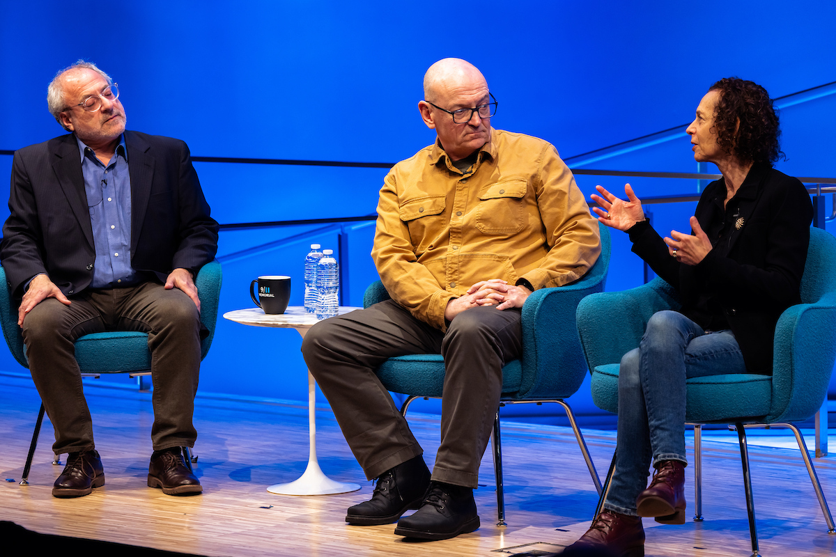 three panelists engage in conversation on stage