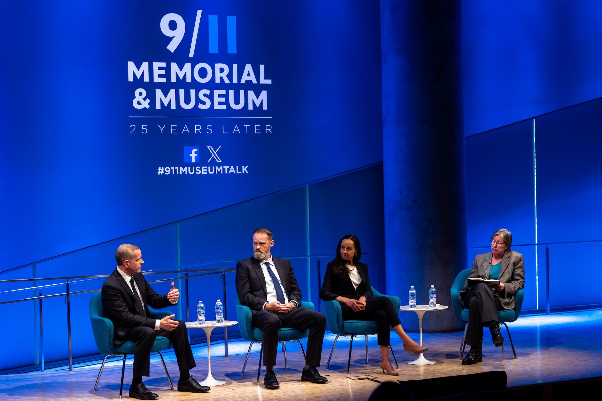 four people sit on stage under the 911 Memorial and Museum logo