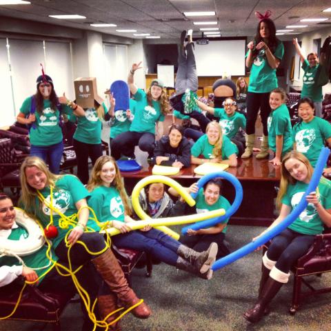 A group of volunteers in green t-shirts, holding blue and yellow balloons