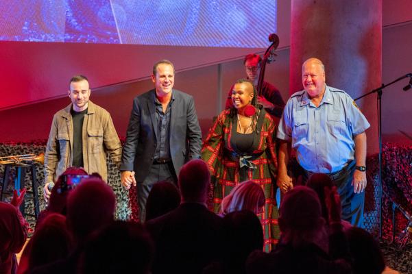 The four performers stand together in a pose