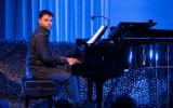 piano player, a man wearing black, plays and faces the audience