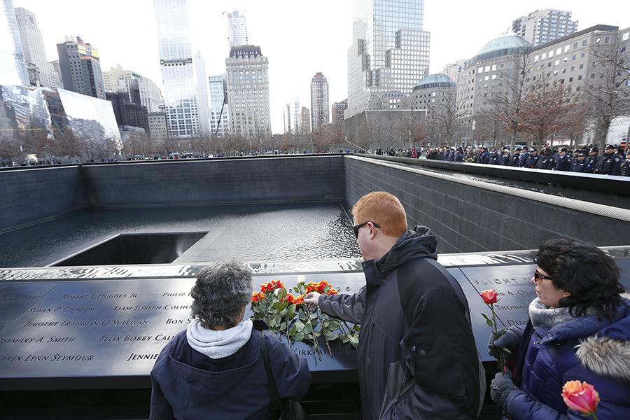 A man and two women place roses at names on the 9/11 Memorial during a ceremony marking the victims of the February 26, 1993 bombing.