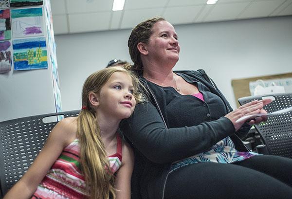 A young girl and a woman listen to a special guest reading at the Museum’s Education Center.