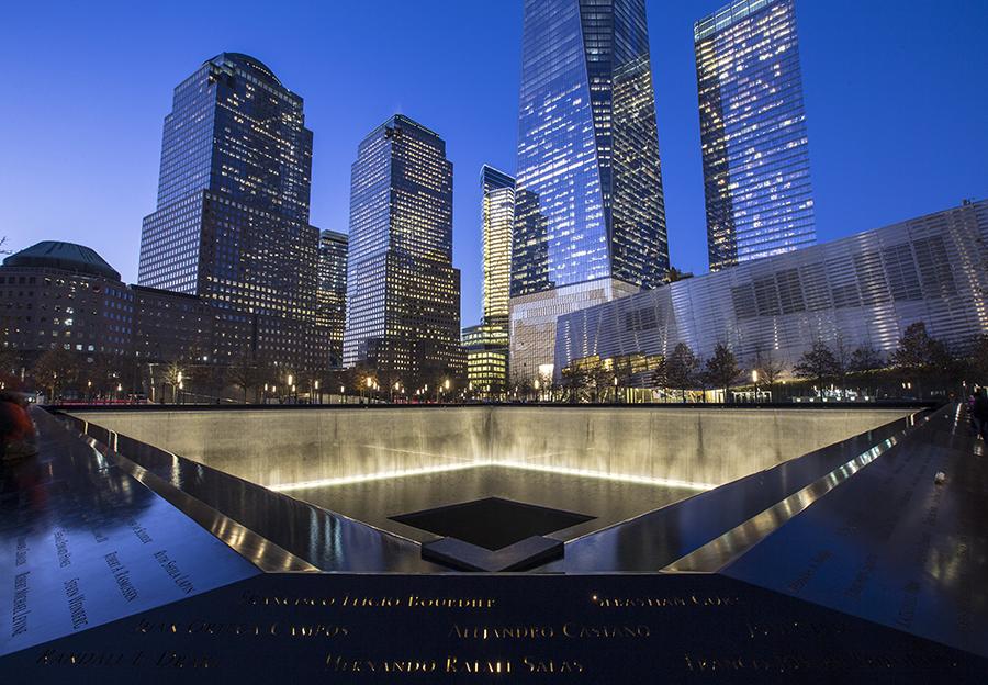 The south pool of Memorial plaza is lit up on a blue, cloudless evening in lower Manhattan.