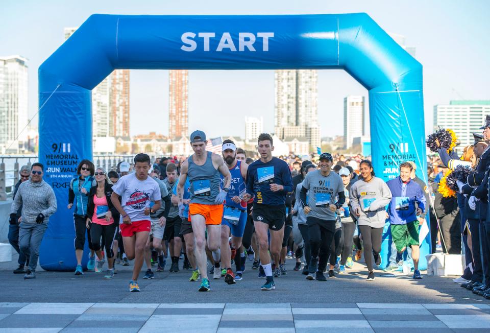 Dozens of participants run at the starting line during the fifth annual 9/11 Memorial 5K Run/Walk and Community Day. The skyline of Jersey City can be seen behind them.