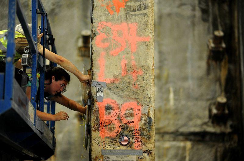 Maureen Merrigan kneels on a cherry picker as she affixes tribute material to the Last Column in Foundation Hall.