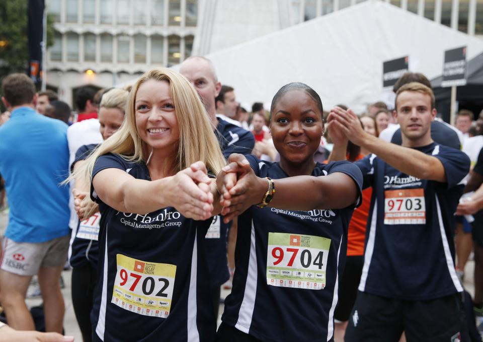 Several men and women participating in the Bloomberg Square Mile Relay stretch out their arms as they prepare for the race.