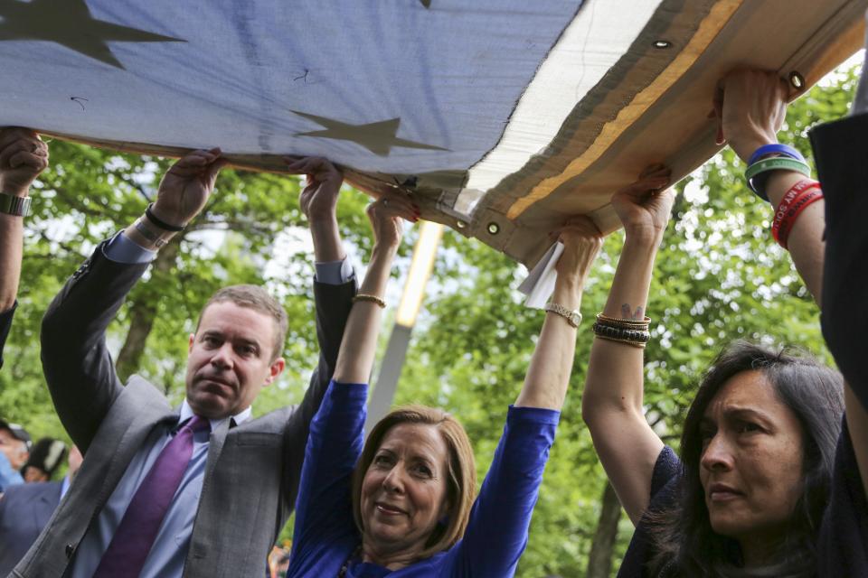 Museum Director Alice Greenwald holds up a flag during the Museum’s opening ceremony in May 2014.