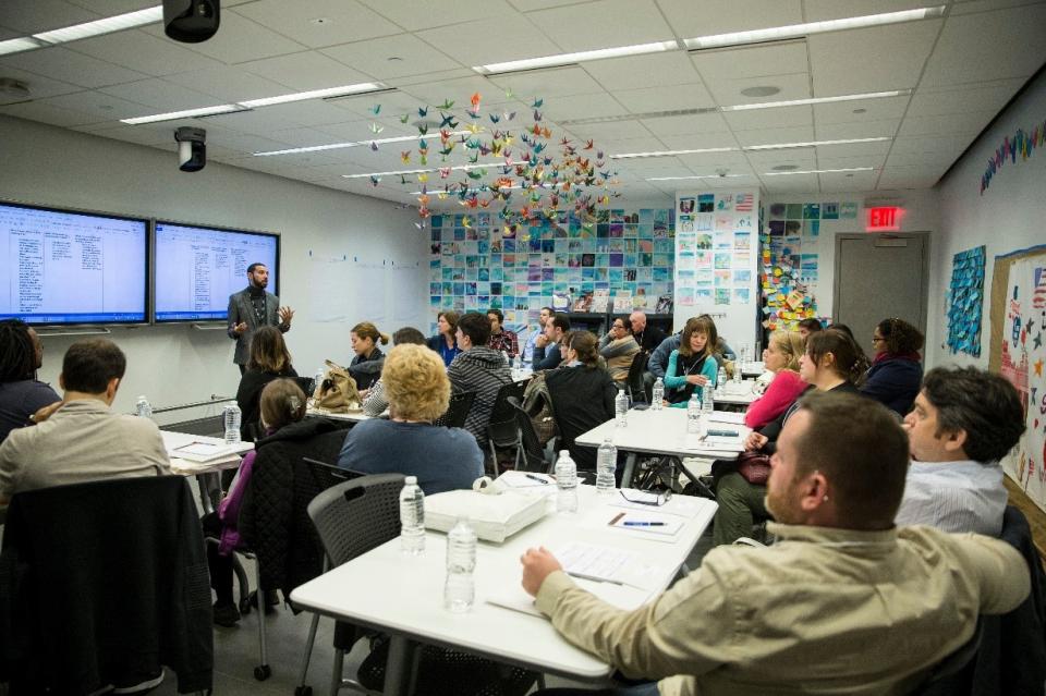 Education specialist Eduardo Quezada stands in front of a group of seated teachers during a presentation at the Education Center.