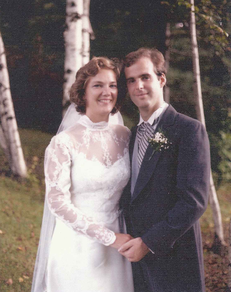 Margaret and John Iskyan pose outside for a photo in their wedding outfits.