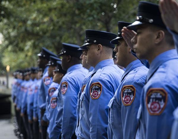 Dozens of formally dressed FDNY probationary firefighters line the south pool of the Memorial.