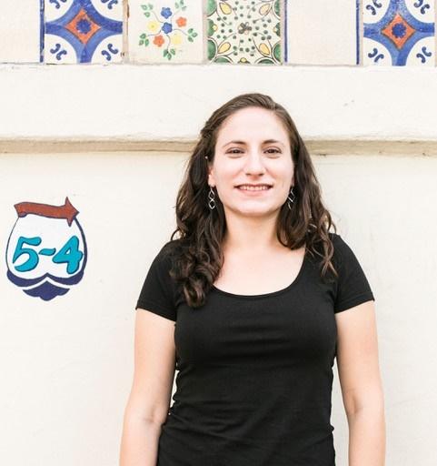 Lila Nordstrom, founder of StuyHealth, poses for a photo in front of a tile wall.