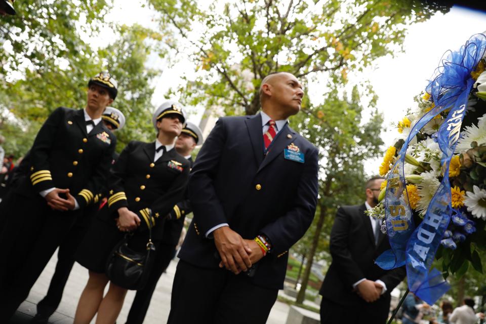 U.S. Naval officers and veterans stand at the Memorial plaza.