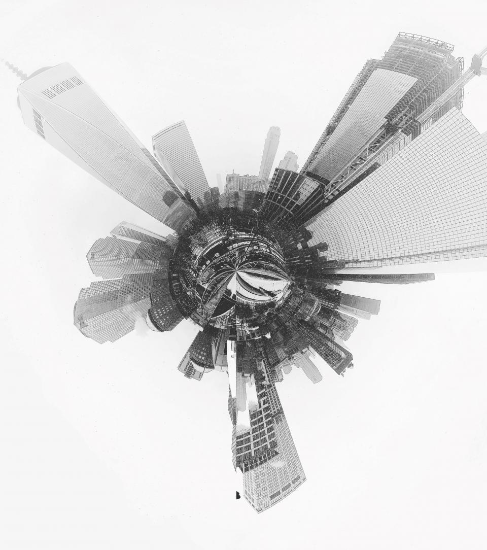A black and white photograph of the World Trade Center site made up of more than 50 still images shows the Memorial, One World Trade Center, and other buildings emerging from a central, circular point. This creates a “tiny planet” photo effect that makes it appear the World Trade Center site is rising out of a small planet.