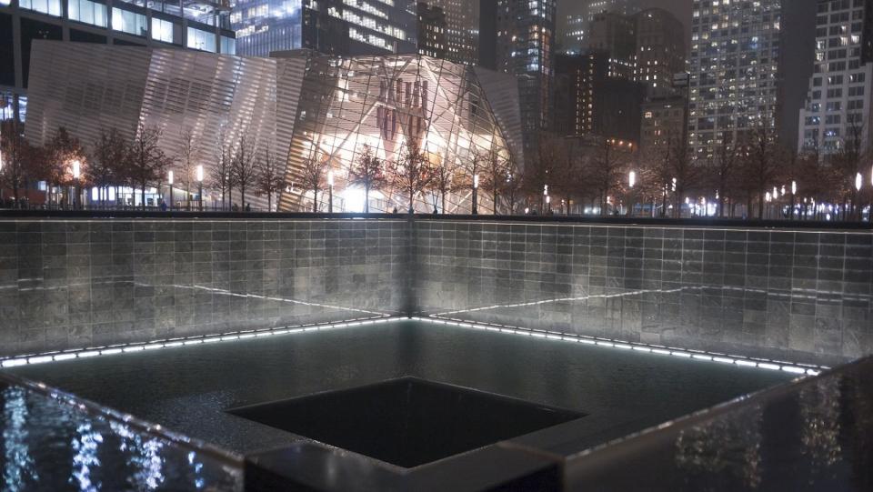 A shot of a memorial pool at dusk. The facade of the museum is visible in the background.