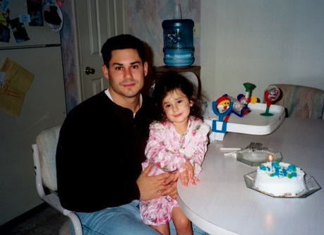 A young father and toddler daughter sit together at a white kitchen table